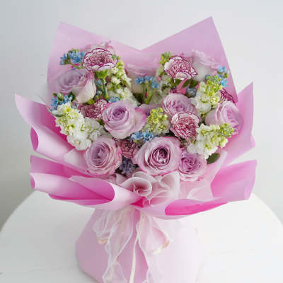 Pink bouquet of roses and carnations wrapped in pink paper