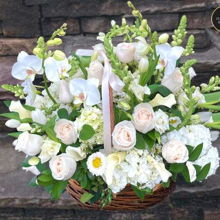 Large basket of white orchids, roses, hydrangeas and calla lilies with soft peach accents.