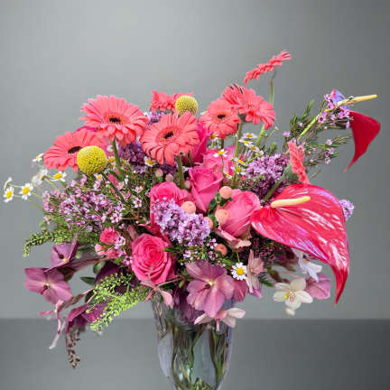 Pink mixed bouquet in a clear glass vase with gerbera daisies and roses