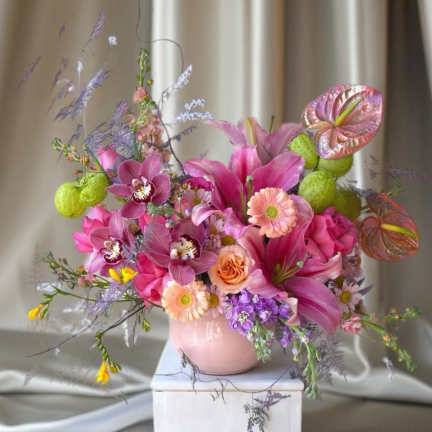 Pink and purple floral arrangement in a pale pink vase