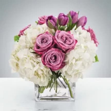 Pink roses and white flowers arranged in a clear square vase