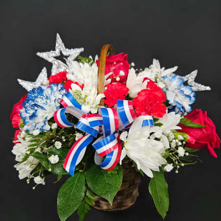 Basket of red, white, and blue flowers with star decorations and ribbon