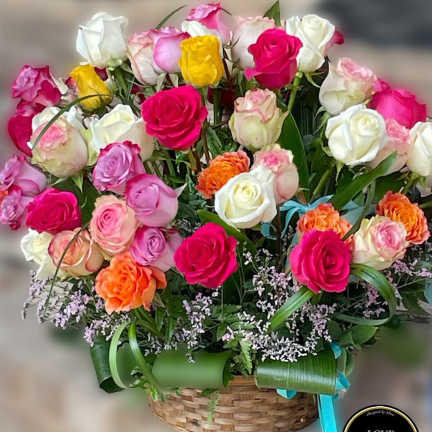 Basket arrangement of bright pink, white, yellow, and orange roses with filler flowers