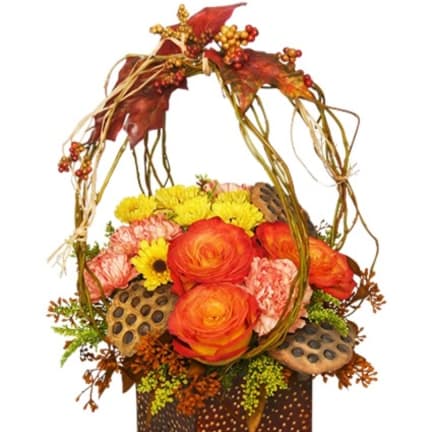 Autumn floral basket with orange roses, yellow mums, and dried leaves