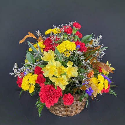 Mixed bouquet in a woven basket with red, yellow, and purple flowers