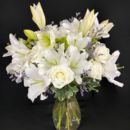 White lilies and roses arranged in a glass vase