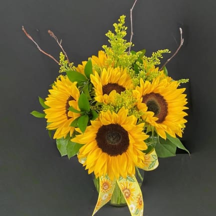 Sunflower bouquet in a glass vase with yellow ribbon
