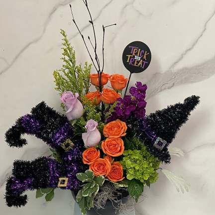 Halloween arrangement with orange and purple roses in a black container