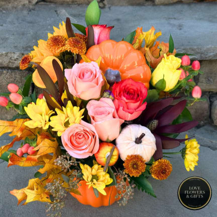 Autumn floral arrangement in a pumpkin container with roses and mums
