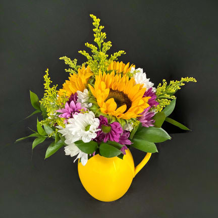 Sunflower and daisy bouquet in a yellow pitcher vase