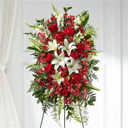 Standing floral spray with red roses and white lilies on a black easel