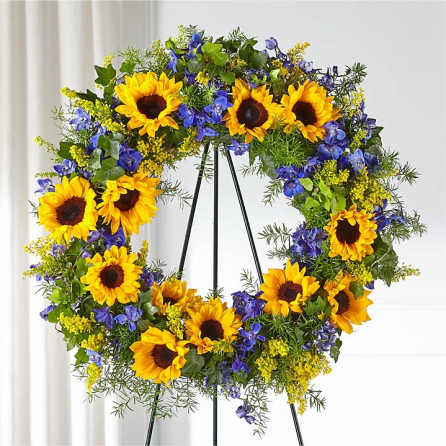 Sunflower wreath with blue and yellow flowers on a black stand
