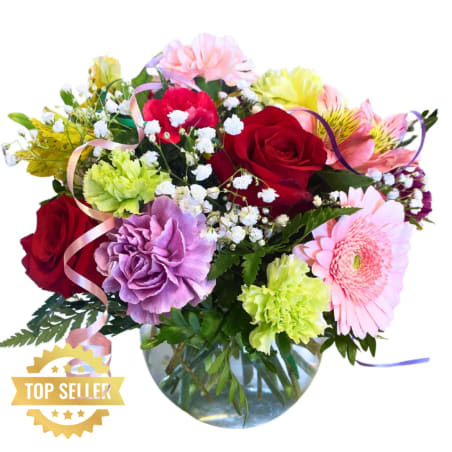 Mixed bouquet of roses, carnations, and gerbera daisies in a glass vase
