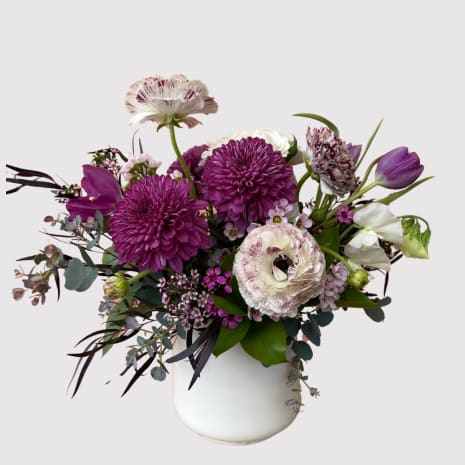 Purple and white mixed bouquet in a white vase
