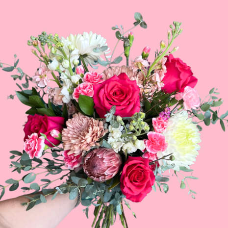 Handheld bouquet of pink roses, chrysanthemums, and carnations