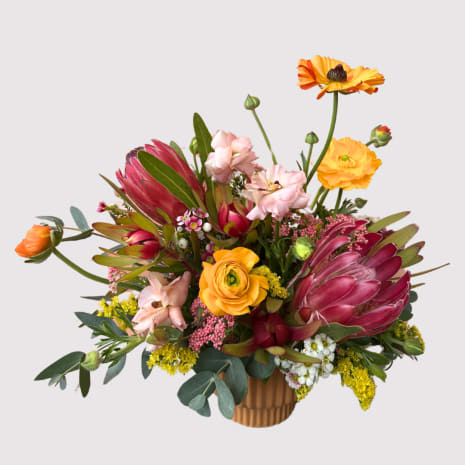 Colorful mixed bouquet in a ribbed vase with pink and orange blooms
