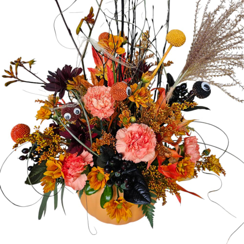 Autumn floral arrangement in a pumpkin-shaped container with pink and orange blooms