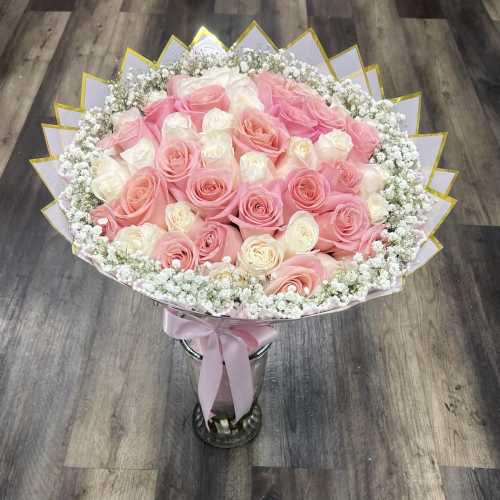 Bouquet of pink and white roses with baby's breath in a silver vase