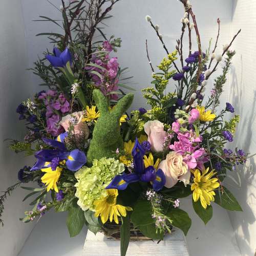Mixed floral arrangement with a green bunny topiary and arched branches