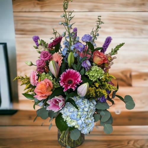 Mixed bouquet in a glass vase with pink, purple, blue, and orange flowers