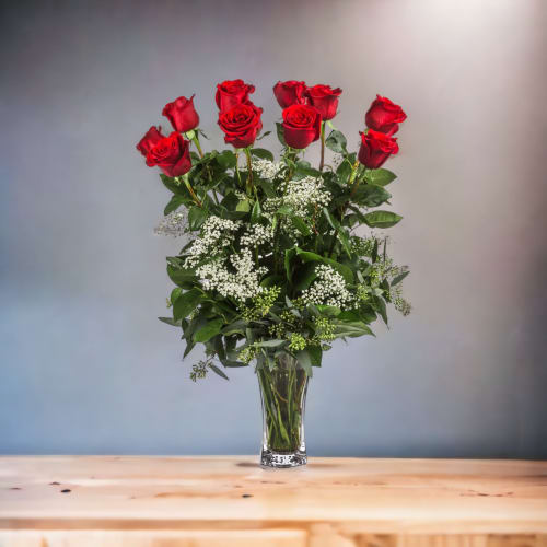 Red roses arranged in a clear glass vase with white filler flowers
