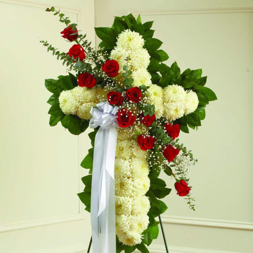 Cross-shaped floral spray with red roses and white chrysanthemums on a stand