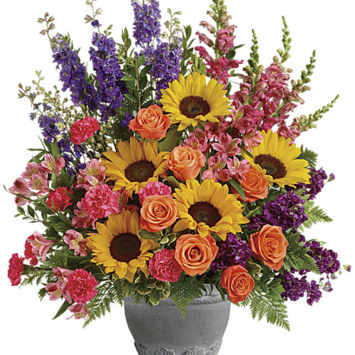 Colorful bouquet with sunflowers, orange roses, and purple flowers in a gray vase