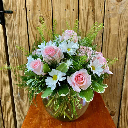 Pink roses and white daisies arranged in a glass vase