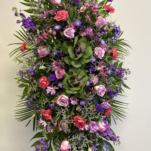 Tall standing spray of pink, purple, and red flowers on an easel