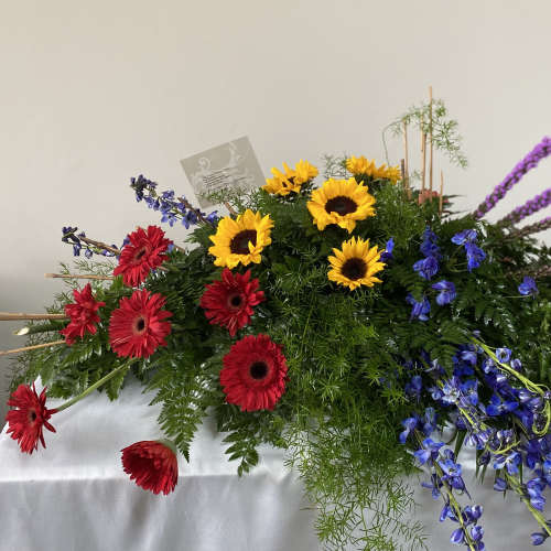 Large mixed floral arrangement with sunflowers, red gerberas, and purple spikes