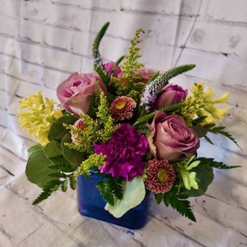 Mixed bouquet of pink roses and purple flowers in a blue vase