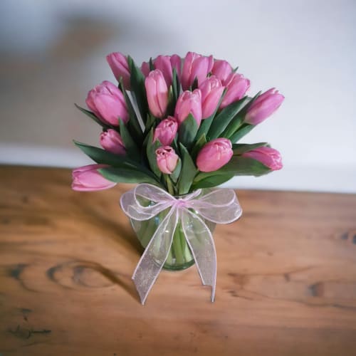 Pink tulips in a clear glass vase with a sheer ribbon