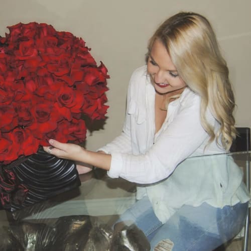 Large red rose arrangement with yellow orchids in a black vase