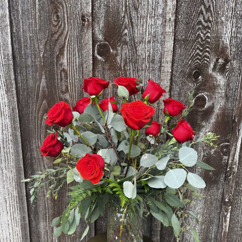 Red roses in a clear glass vase with eucalyptus