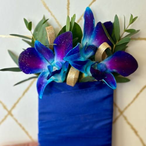 Blue orchid corsage with gold ribbon on a wrapped base