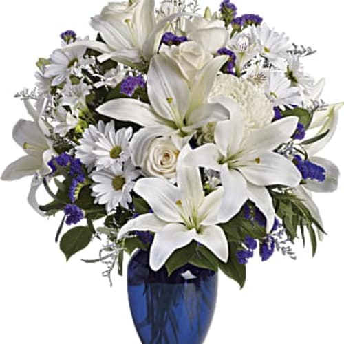 White lilies and daisies arranged in a blue vase