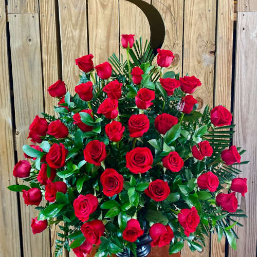Large bouquet of red roses in a black vase with a crescent moon pick