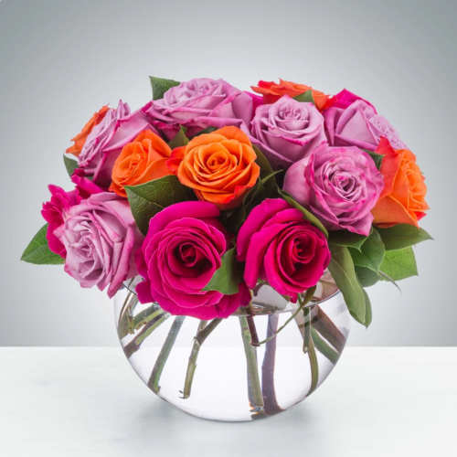 Bouquet of pink, lavender, and orange roses in a clear glass vase