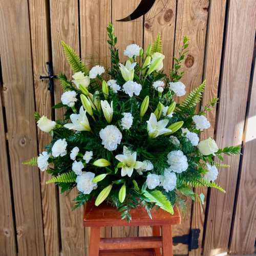 White lilies and carnations in a standing floral arrangement