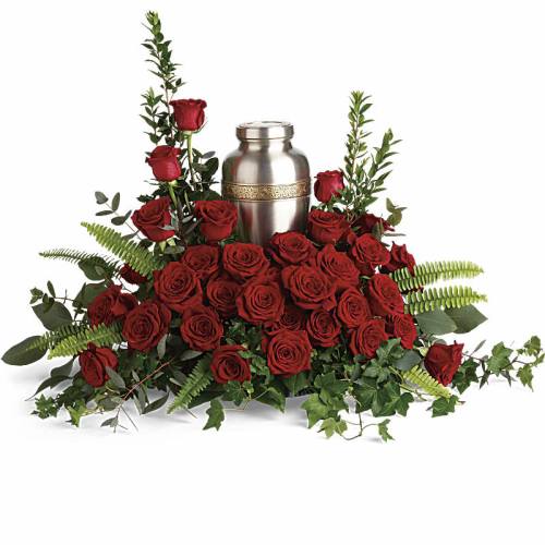 Red roses arranged around a silver urn with greenery