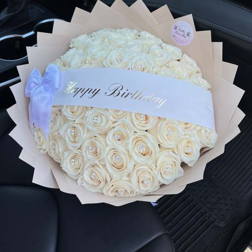 Cream rose bouquet with a Happy Birthday ribbon in a car seat