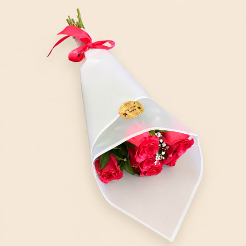 Bouquet of bright pink roses wrapped in white paper with a red ribbon