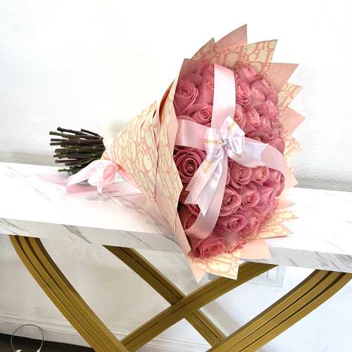 Pink rose bouquet wrapped in peach paper with a satin ribbon