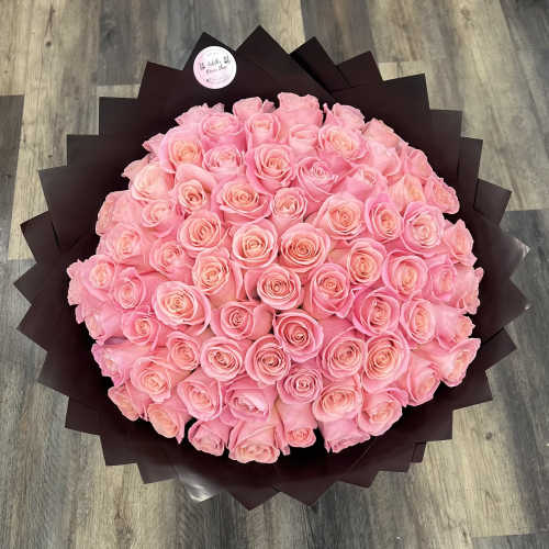 Large bouquet of pink roses wrapped in dark paper