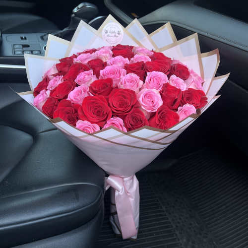 Large bouquet of pink and red roses wrapped in white paper