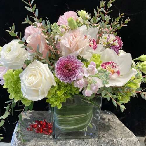 Mixed bouquet of white, pink, and green flowers in a clear glass vase