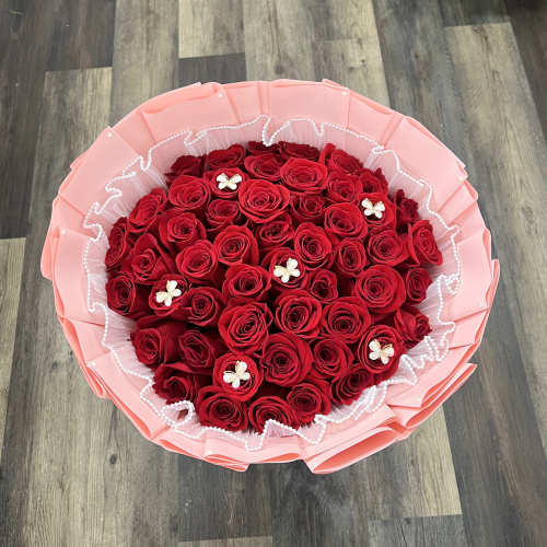 Round bouquet of red roses wrapped in pink paper
