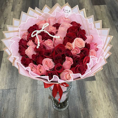 Bouquet of red and pink roses in pink wrapping with a glass vase