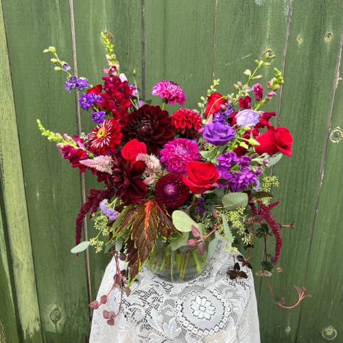 Mixed bouquet of red, purple, and pink flowers in a glass vase
