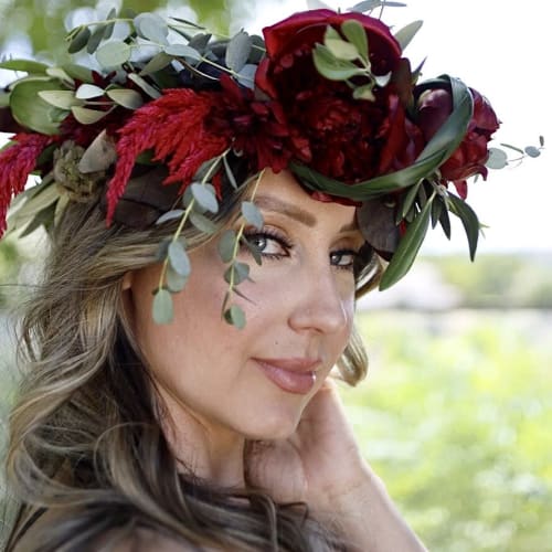 Woman wearing a red floral crown with greenery